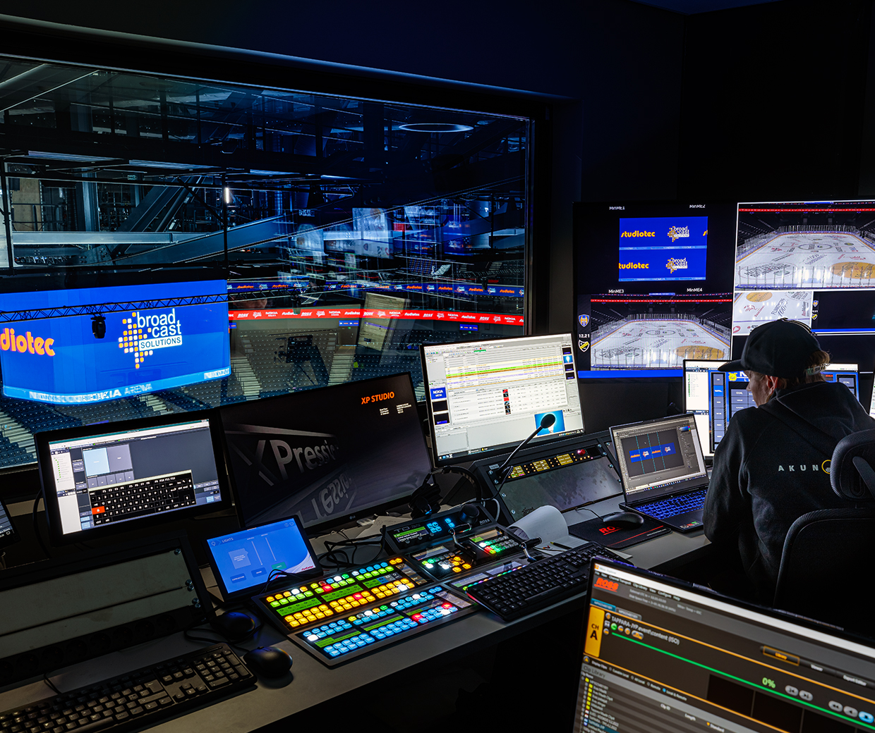 Control room with multiple monitors displaying live sports feeds, real-time statistics, and data visualizations during a game