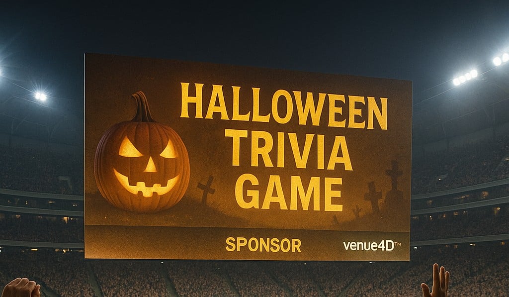 Wide stadium view with fans celebrating during a Halloween-themed trivia game on the video board, featuring sponsor branding and venue4D™ interactive fan engagement.